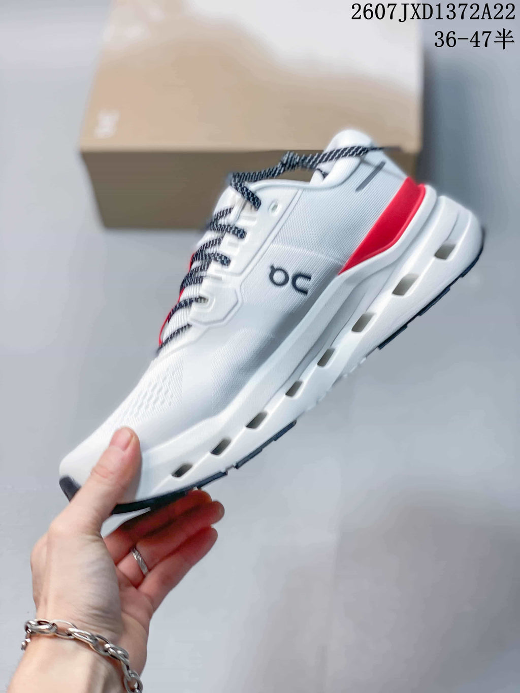 Side view of the white sneaker showing On branding, red heel detail, black outsole accents, and sole openings.