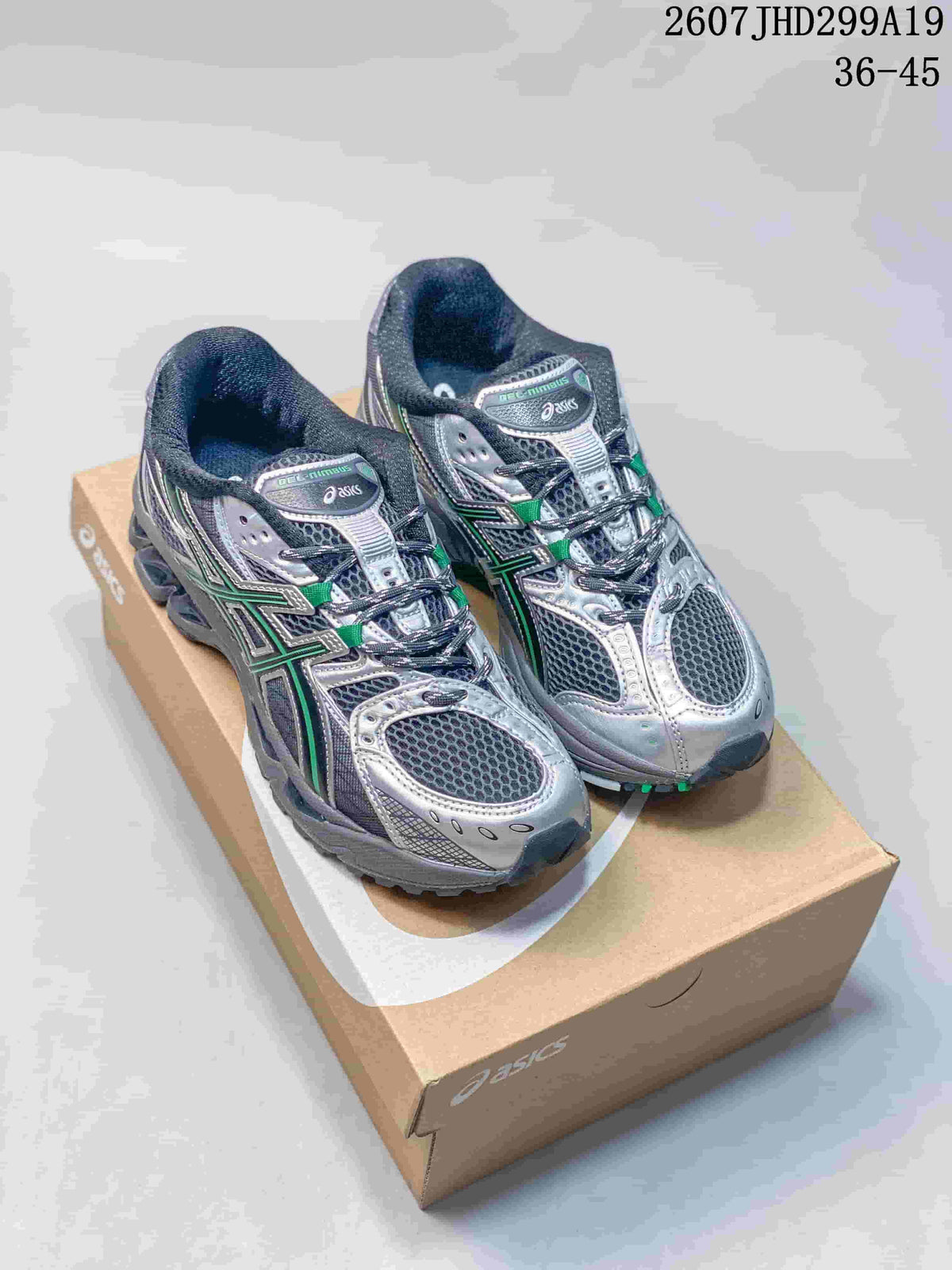 Pair of silver, dark gray and green ASICS Gel-Nimbus 10.1 sneakers displayed on an ASICS shoebox; image text shows 2607JHD299A19 and 36–45.