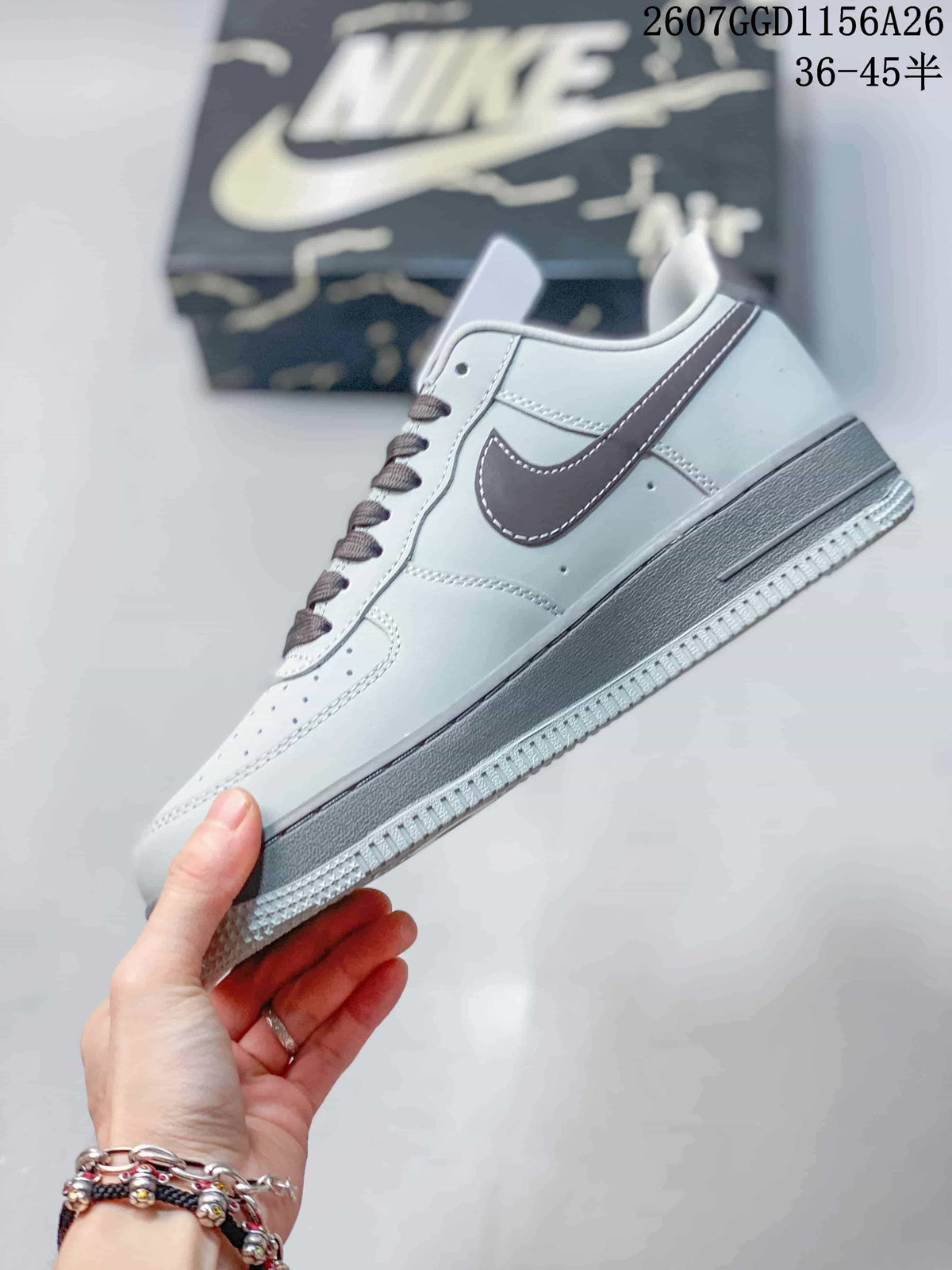 Side view of a gray low-top sneaker showing the dark Swoosh, contrast stitching, perforated upper, and layered sole.
