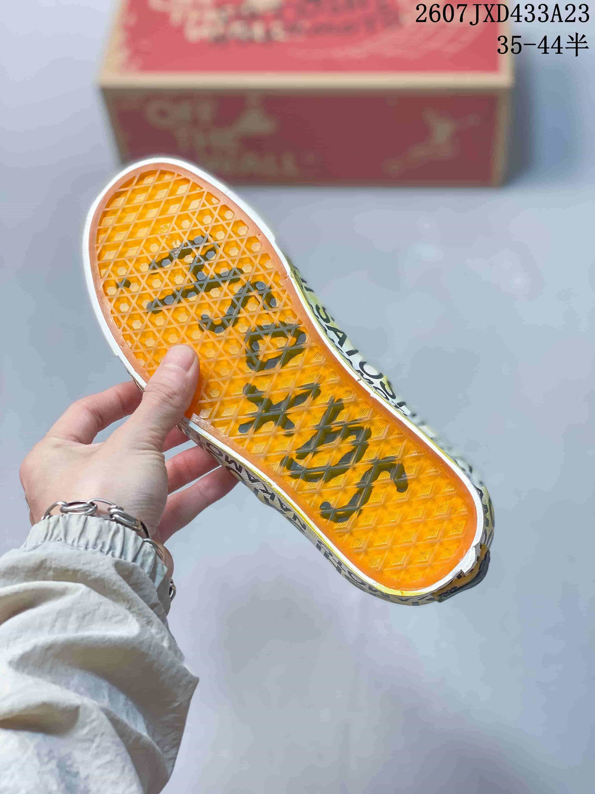 Bottom view of the sneaker showing the translucent orange waffle-pattern rubber outsole and printed tread details.