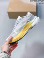 Side view of the white On sneaker with layered upper panels, yellow midsole, and black outsole edge.