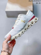 Side view highlighting the textured white upper, gold branding, red heel accent, and segmented sole.