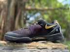 Opposite side profile showing the black upper, gold Swoosh, heel panel, and visible outsole edge.