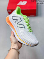 White New Balance running sneaker with a bright green collar and laces and orange midsole detailing.