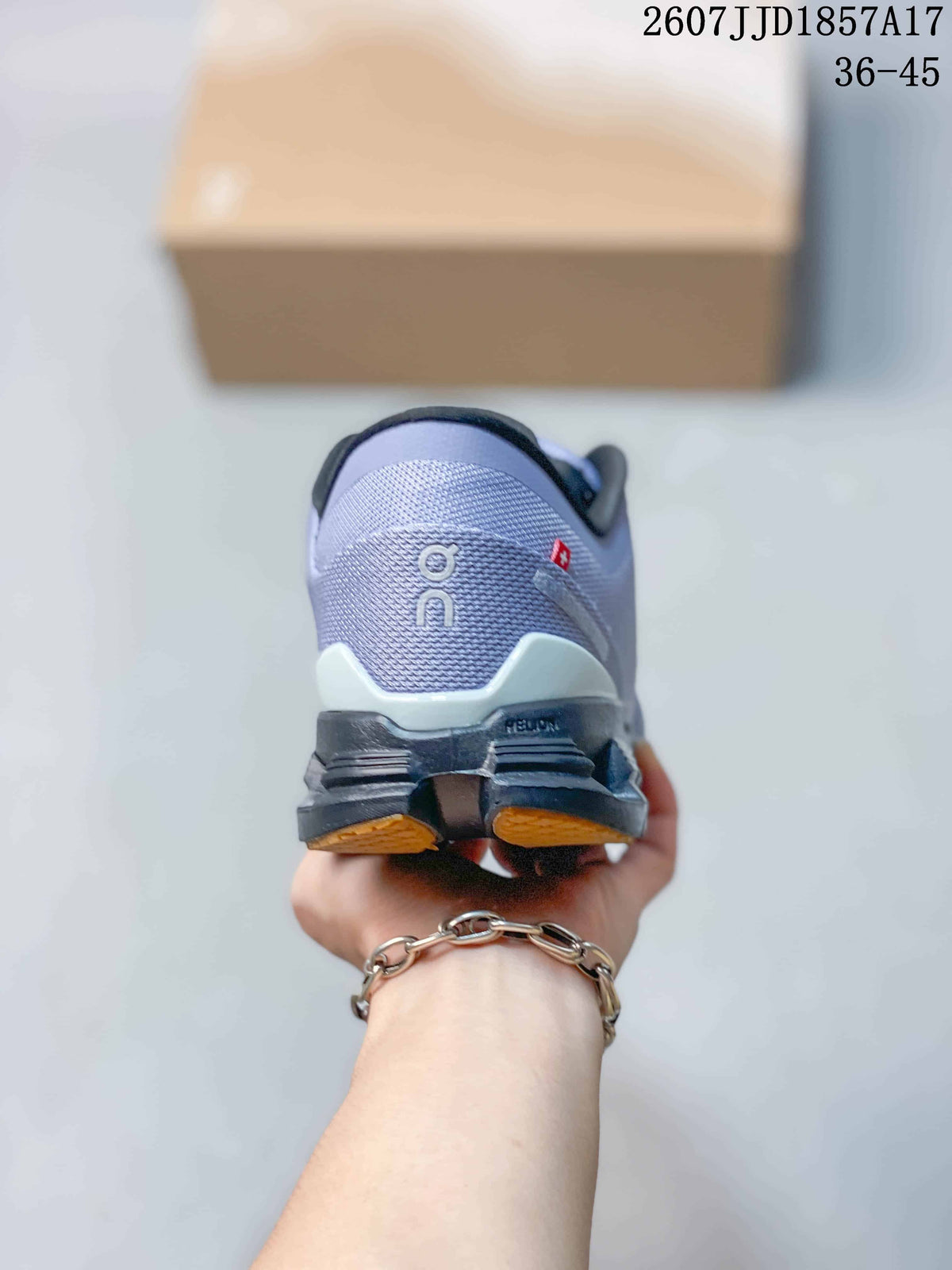 Rear view of the lavender-grey sneaker showing the padded heel, On branding, segmented outsole, and tan outsole sections.