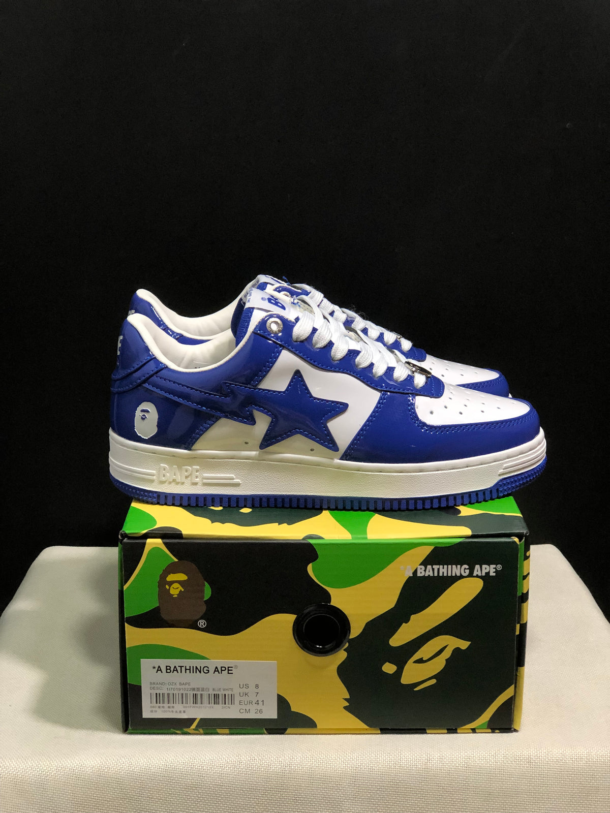 Side view of the blue and white Bape Sta sneakers with star-shaped side panels and a Bape-branded box.