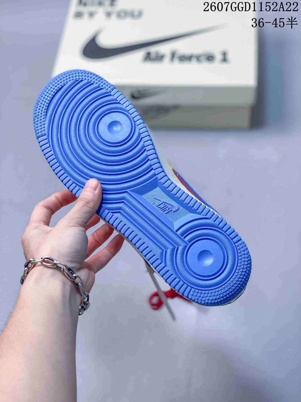 Blue outsole of a Nike Air Force 1 sneaker held in front of its shoebox; image text shows a 36–45.5 size range.