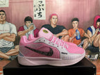 Side view of a pink basketball shoe with gray panels, a black patterned Swoosh, and ROOTS lettering.