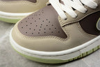 Close-up of the beige and brown perforated toe box, stitching, white laces, and light green outsole edge.