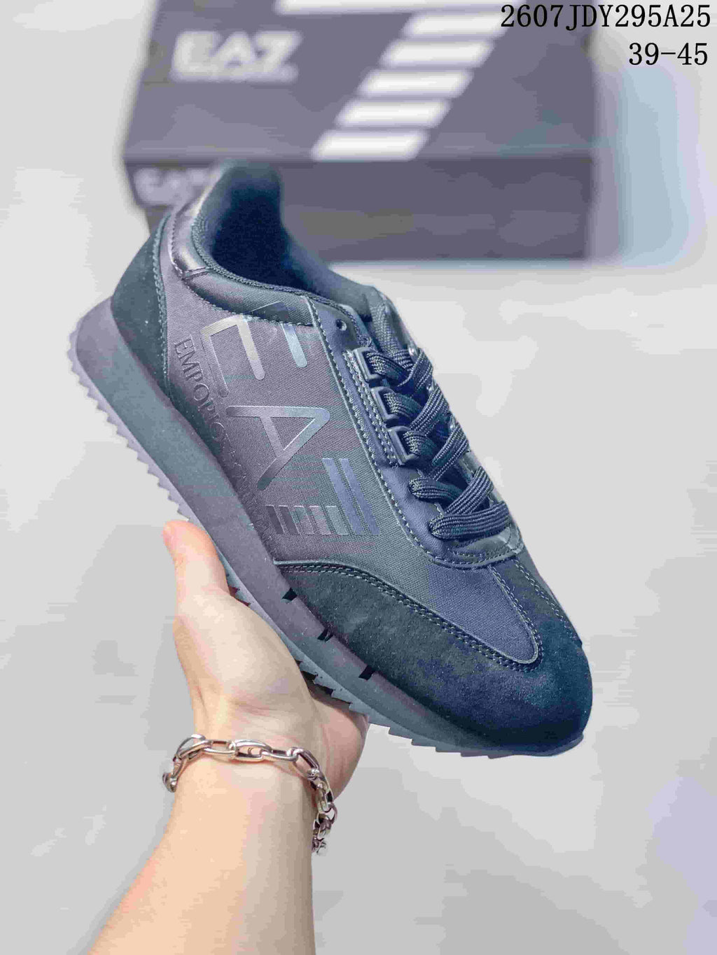 Close-up of an all-dark Emporio Armani EA7 sneaker with tonal side branding, lace-up construction and a dark textured outsole.