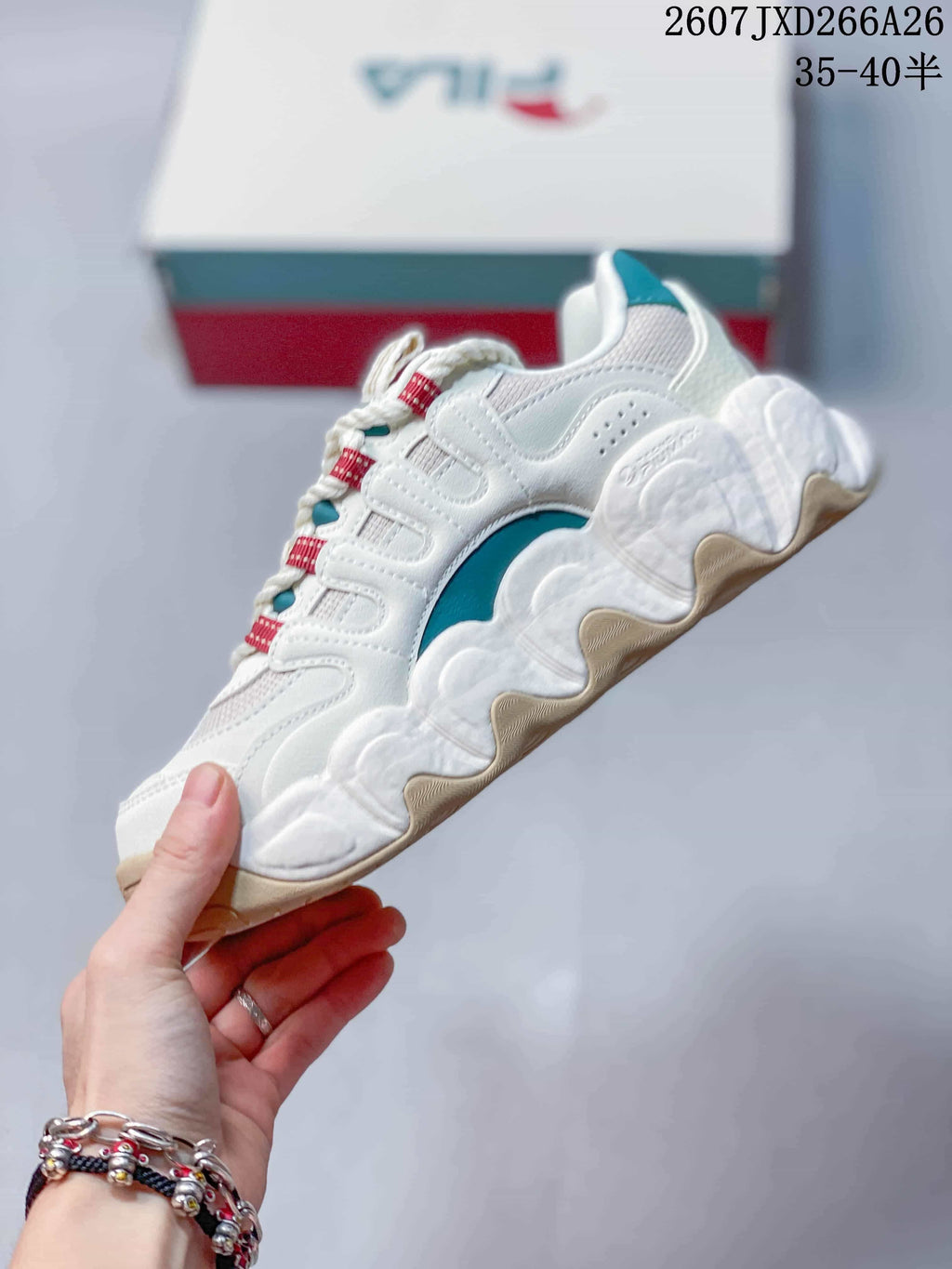 Side view of the white and gray sneaker showing layered panels, teal detailing, and a sculpted sole.