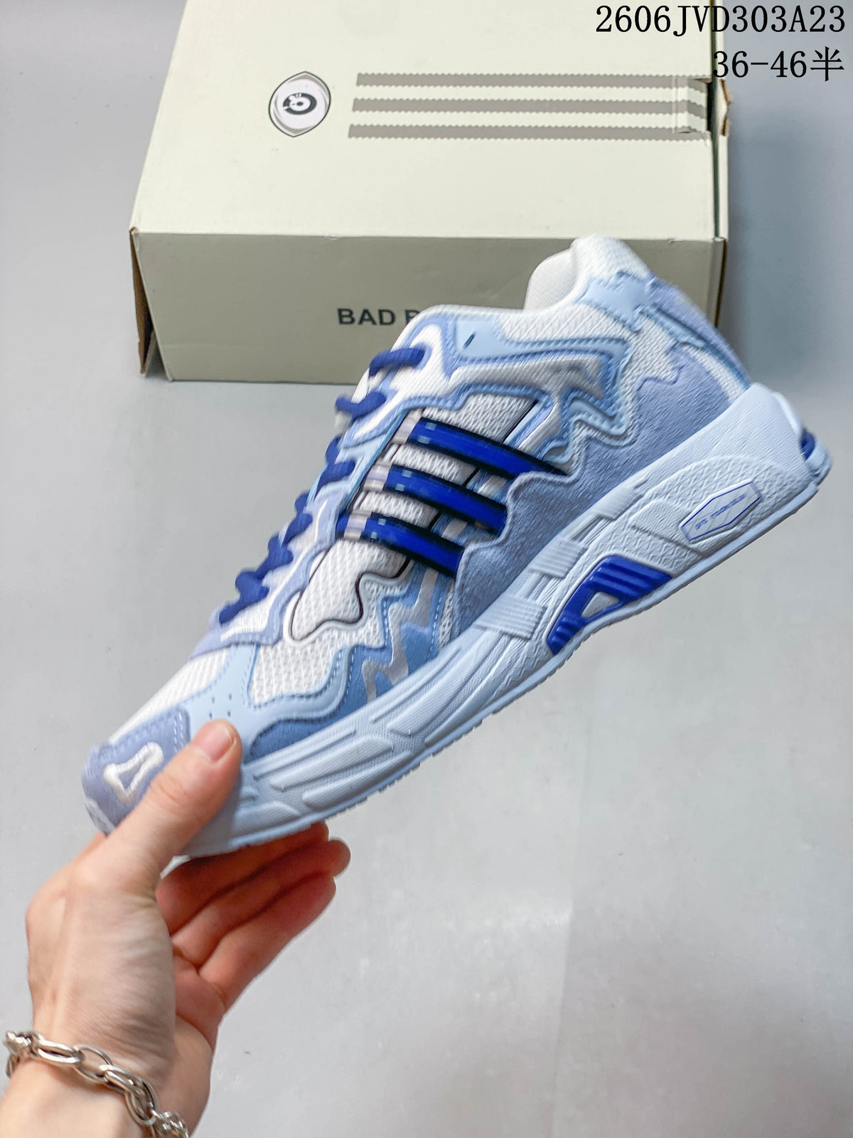 Side view of the white and blue sneaker with dark blue stripes and sculpted sole.