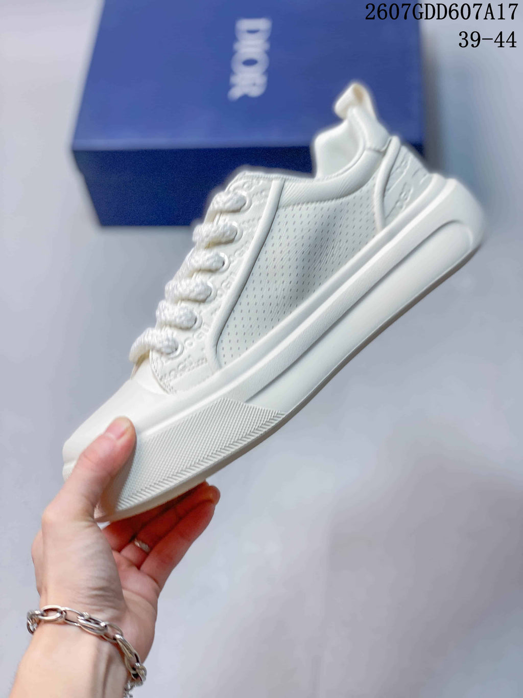 Side view of the white sneaker showing perforated panels, layered sole construction and lace eyelets.