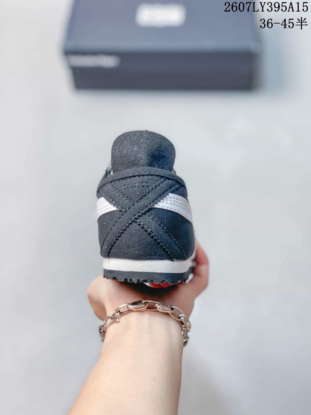 Rear view of the black and white sneaker showing the crossed side stripes, heel panel, white midsole, and textured outsole.