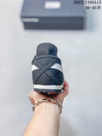 Rear view of the black and white sneaker showing the crossed side stripes, heel panel, white midsole, and textured outsole.