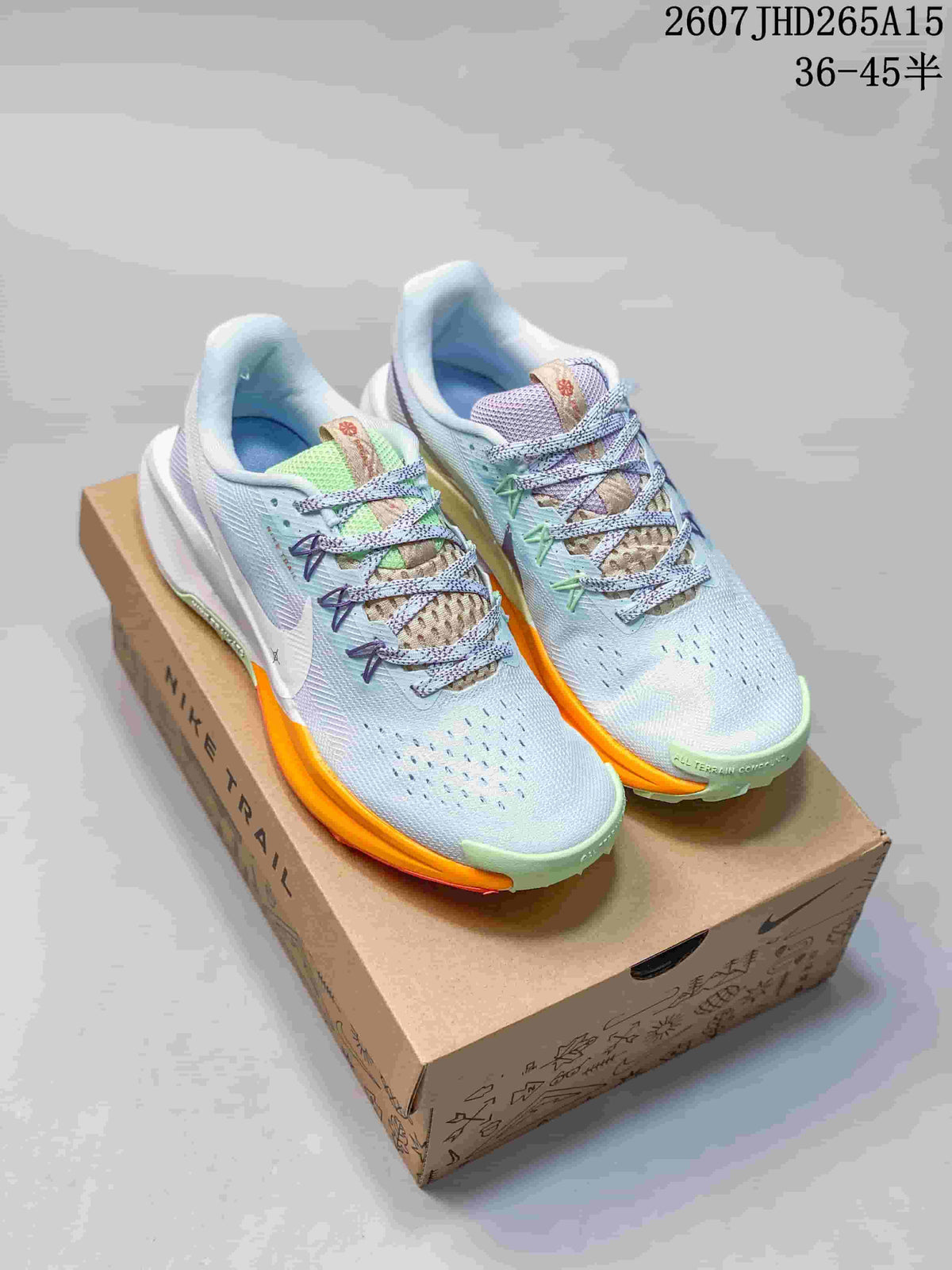 Pair of Nike Pegasus Trail 5 sneakers in light blue with lime green and orange accents, displayed on a shoe box.