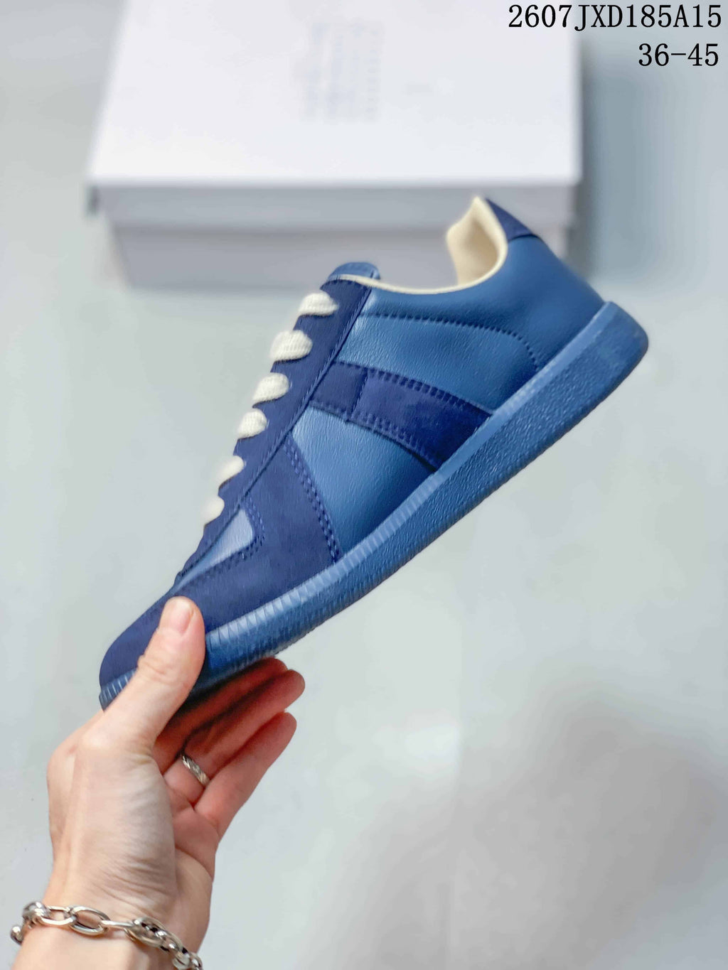 Side view of the blue low-top sneaker showing tonal panels, white laces, and a textured blue rubber outsole.