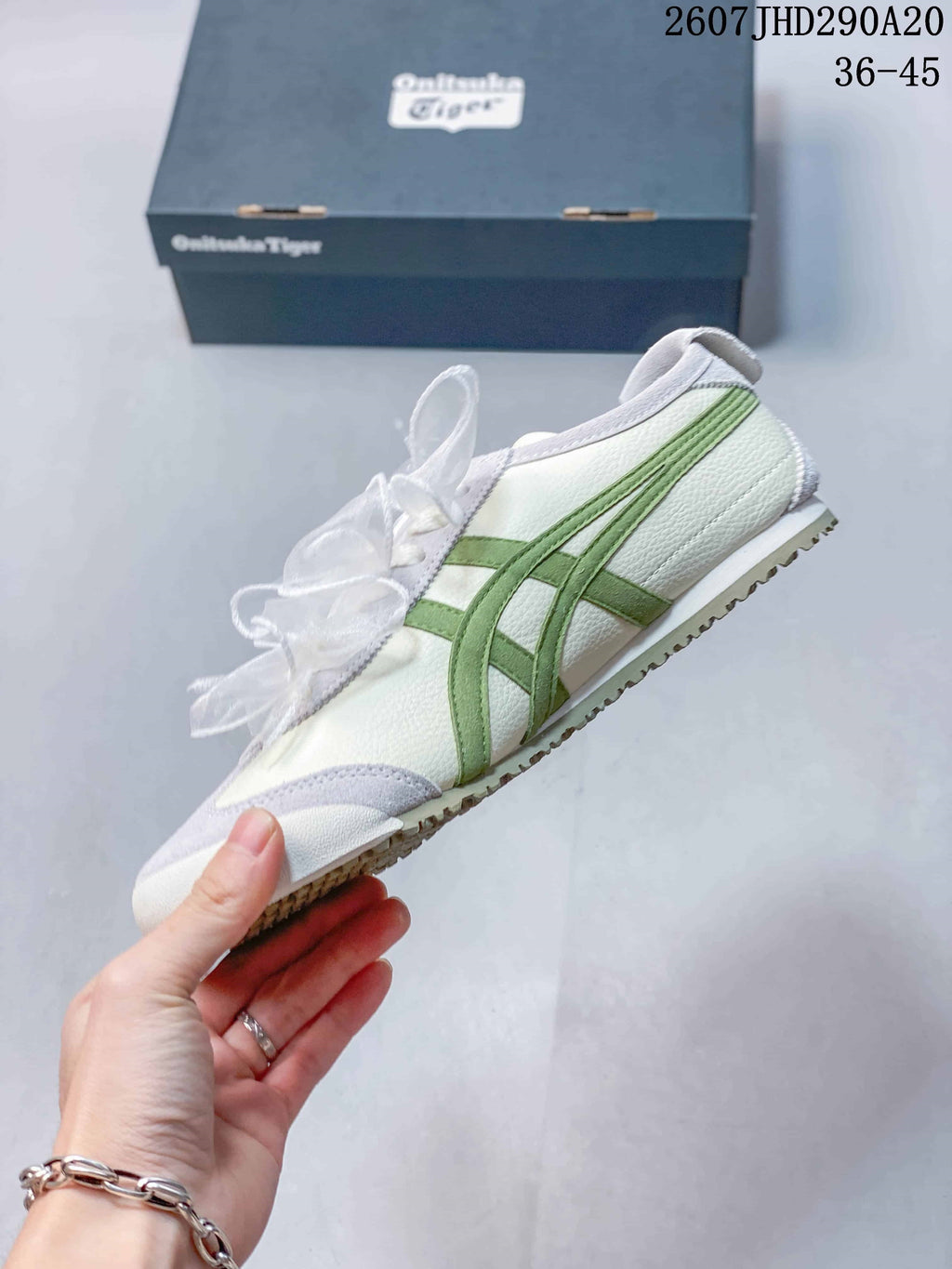 Side view highlighting the white upper, green layered stripes, light gray overlays, and ribbon laces.