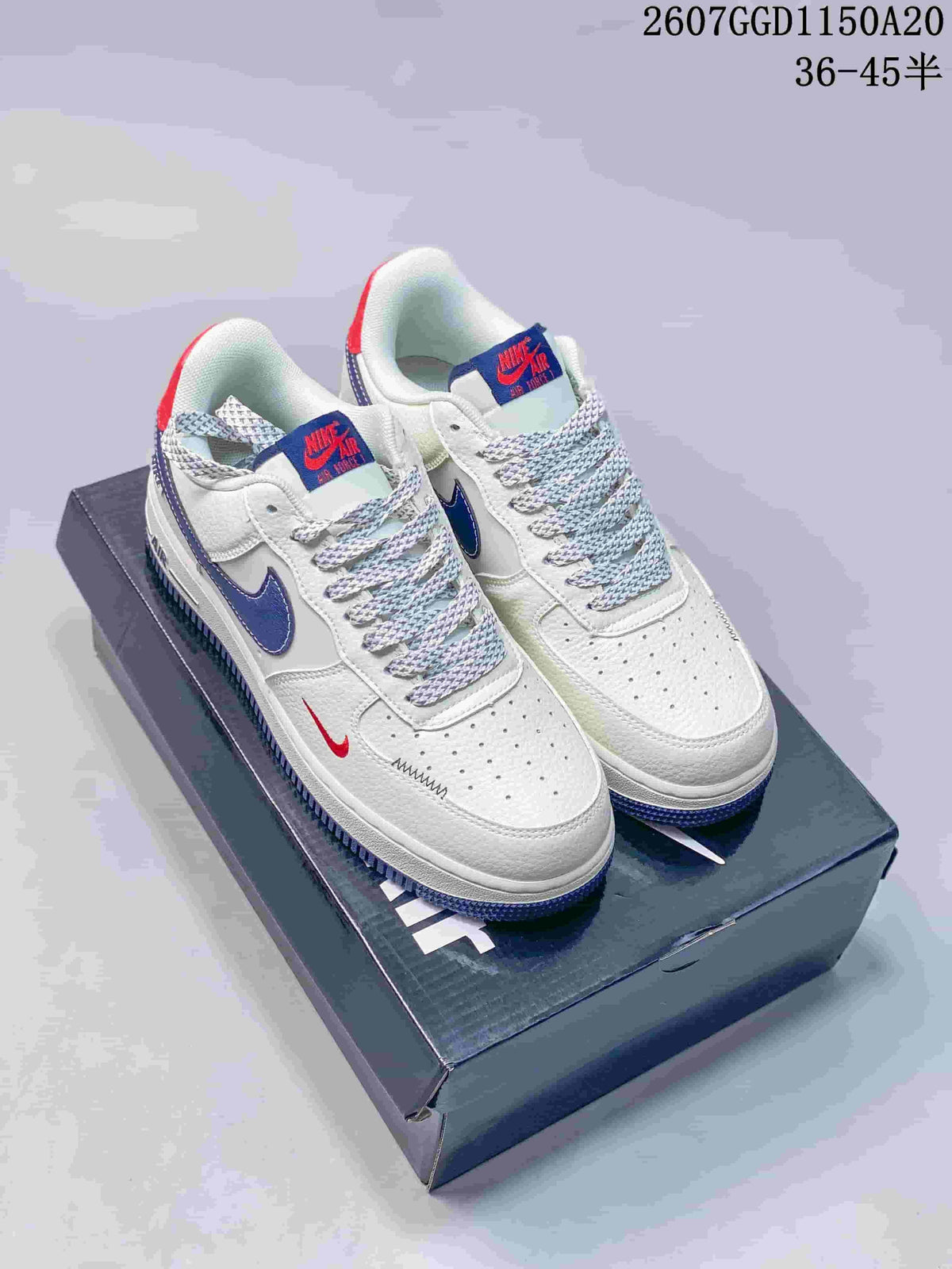 Pair of white low-top Nike sneakers with blue and red accent details, patterned laces, and a perforated toe box.