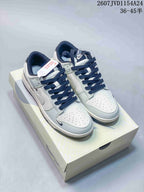 Pair of white and navy Nike SB Dunk Low sneakers displayed on a shoebox, showing navy laces, perforated toe boxes and multiple Swoosh details.