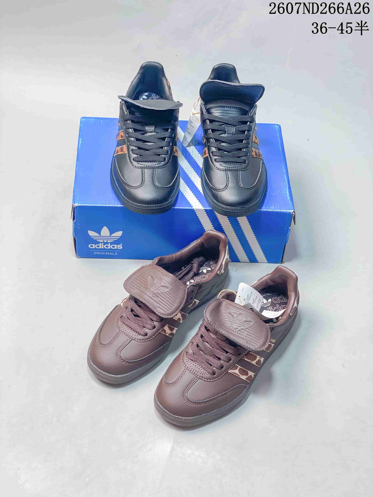 Black and brown adidas Originals Samba sneakers shown together from above on a blue shoebox, highlighting the two colorways and flap tongues.