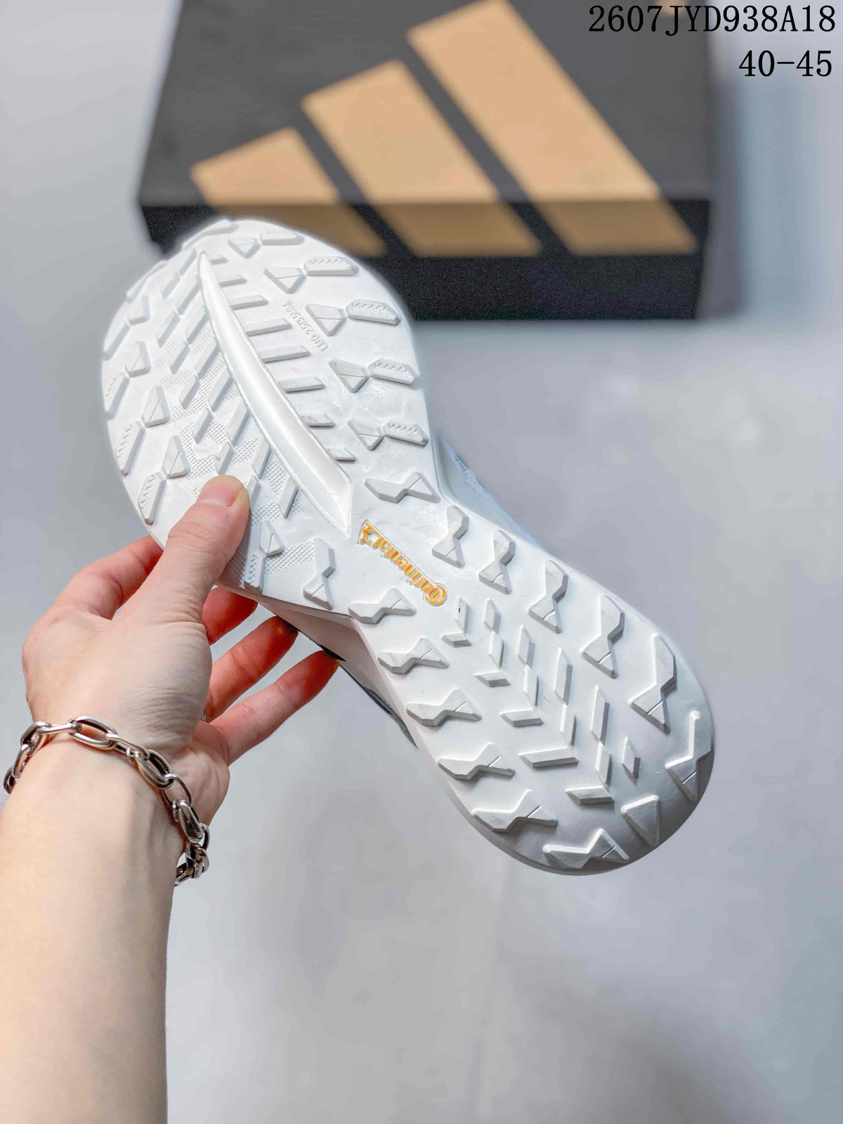Close view of the white outsole with multidirectional tread and TERREX branding, with the Adidas box in the background.