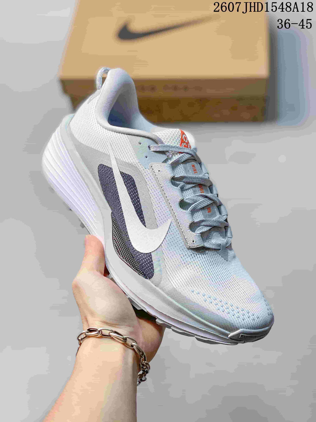Angled side view of the white and gray Nike sneaker showing the lace-up design, side overlays, textured upper, and outsole.