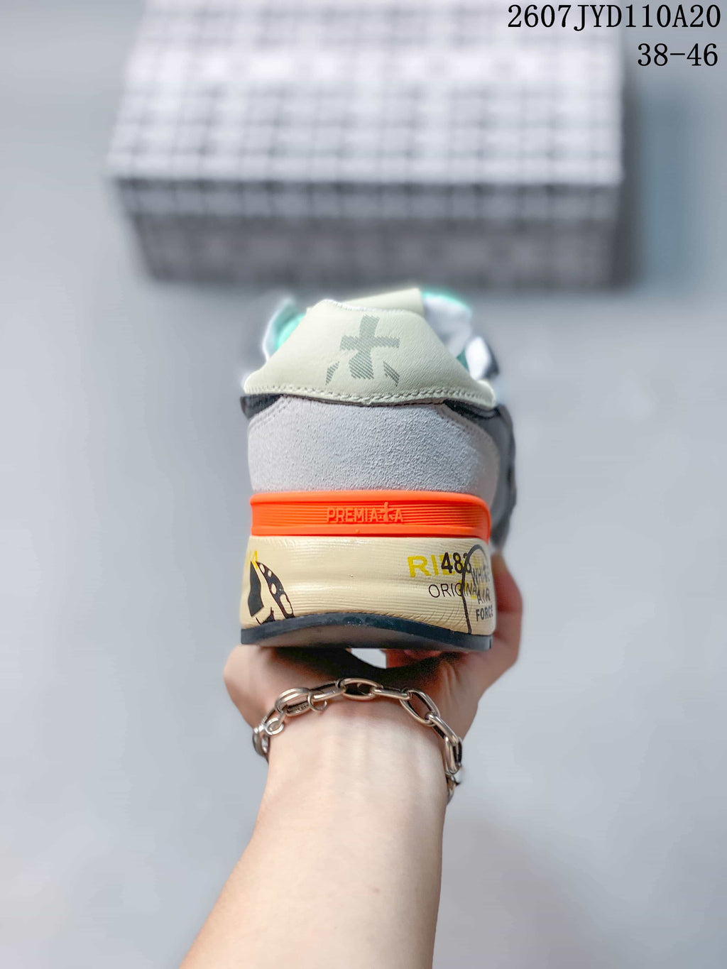 Rear view of a grey Premiata sneaker showing the orange heel detail, printed midsole and branded heel panel; image text shows 2607 TYD110A20 and 38–46.