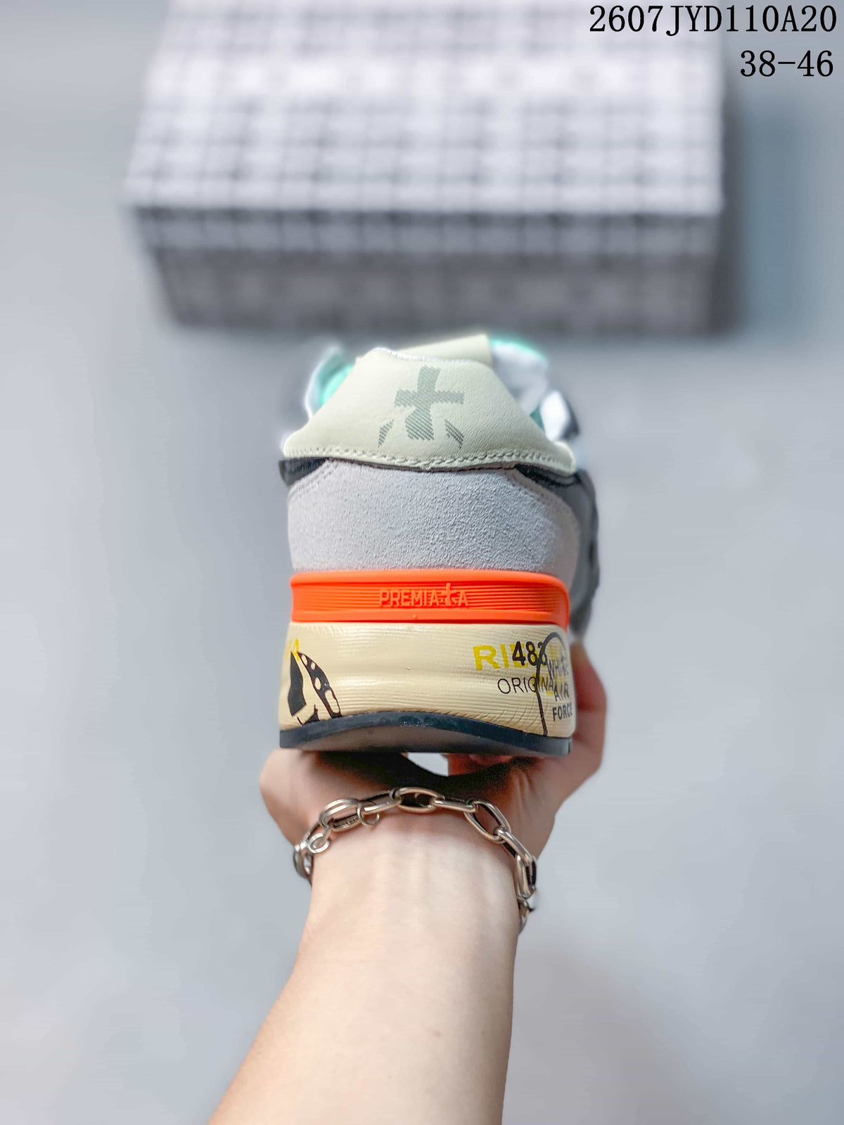 Rear view of a grey Premiata sneaker showing the orange heel detail, printed midsole and branded heel panel; image text shows 2607 TYD110A20 and 38–46.