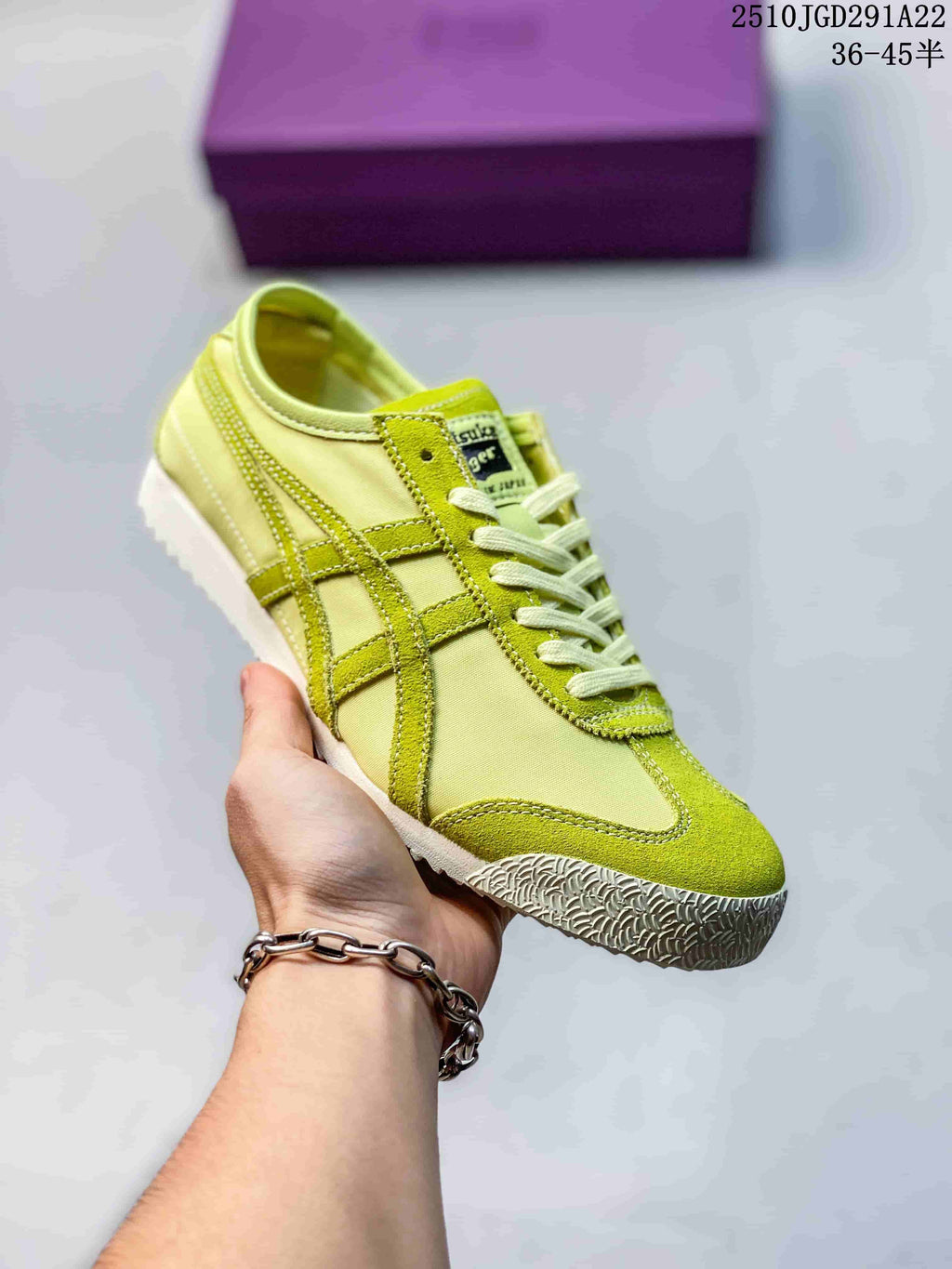 Lime yellow and green Onitsuka Tiger sneaker held in hand, showing tonal contrast stripes and a textured outsole.