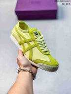 Lime yellow and green Onitsuka Tiger sneaker held in hand, showing tonal contrast stripes and a textured outsole.