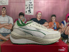 Side profile of an off-white PUMA sneaker with green trim, layered side stripes, and a sculpted sole.