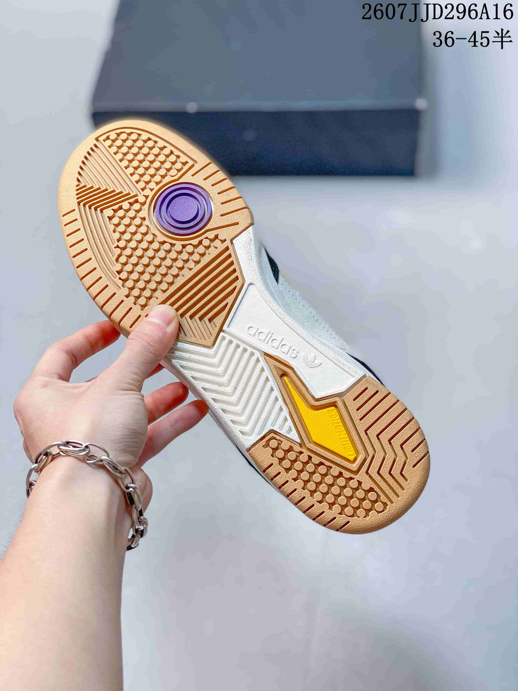 Bottom view of an adidas sneaker showing the gum-colored outsole with patterned traction and trefoil branding.