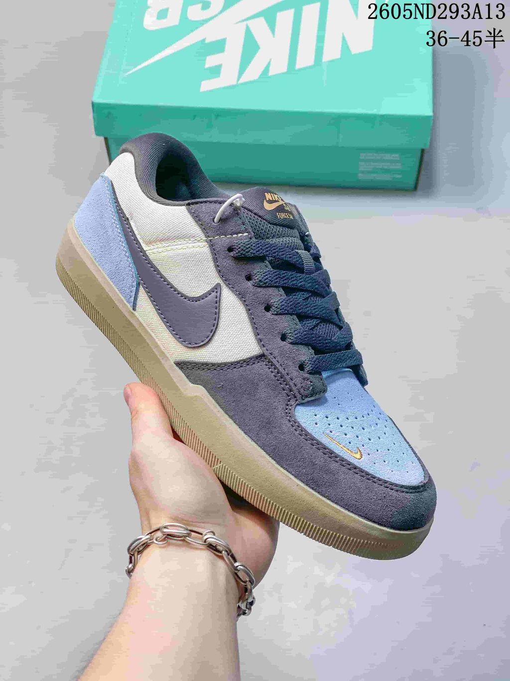 Angled side view of the sneaker showing the light blue perforated toe, dark overlays, contrasting Swoosh and gum-toned outsole.
