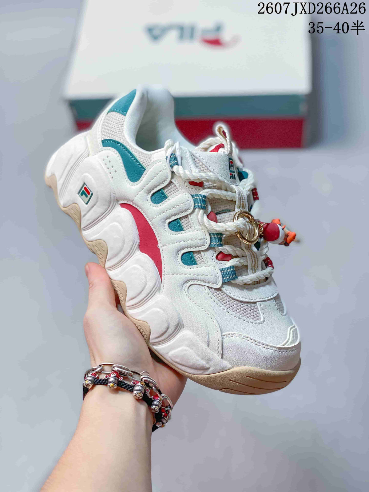 Angled side view of the FILA Croissant sneaker showing white panels, teal and red accents, and a beige outsole edge.
