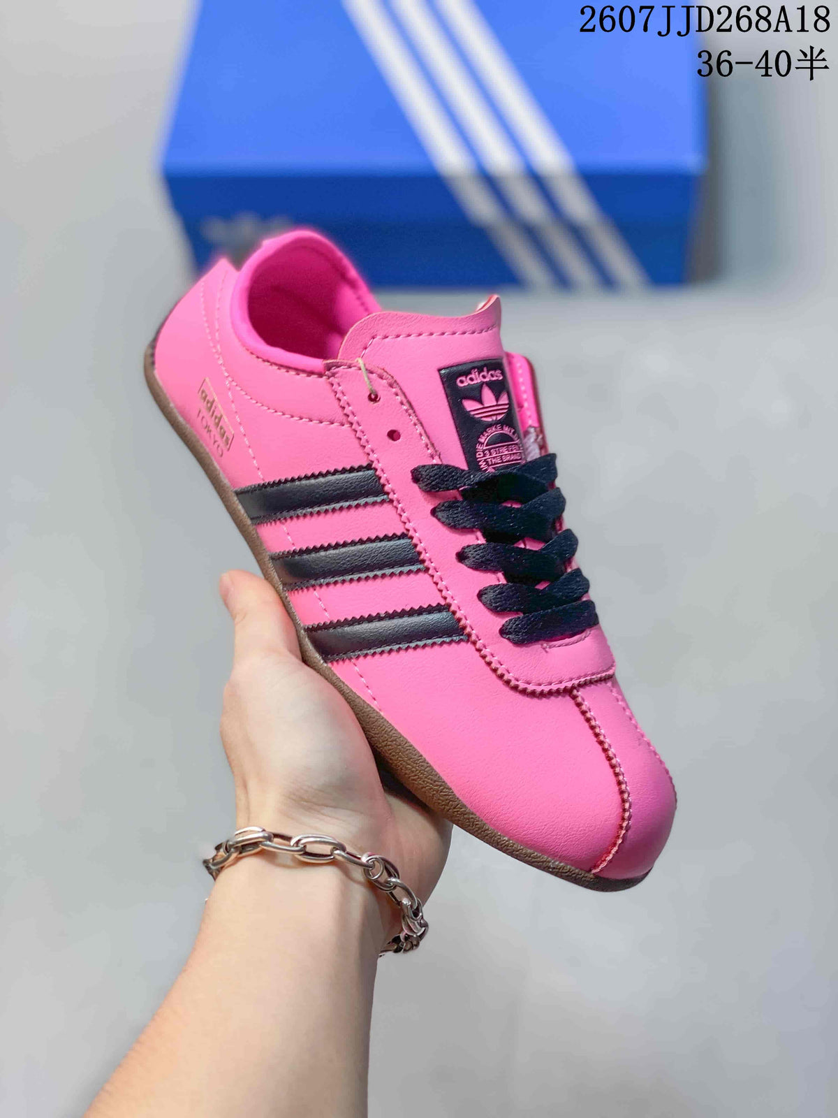 Angled side view of the pink adidas sneaker showing black stripes, lace-up construction, and tongue branding.