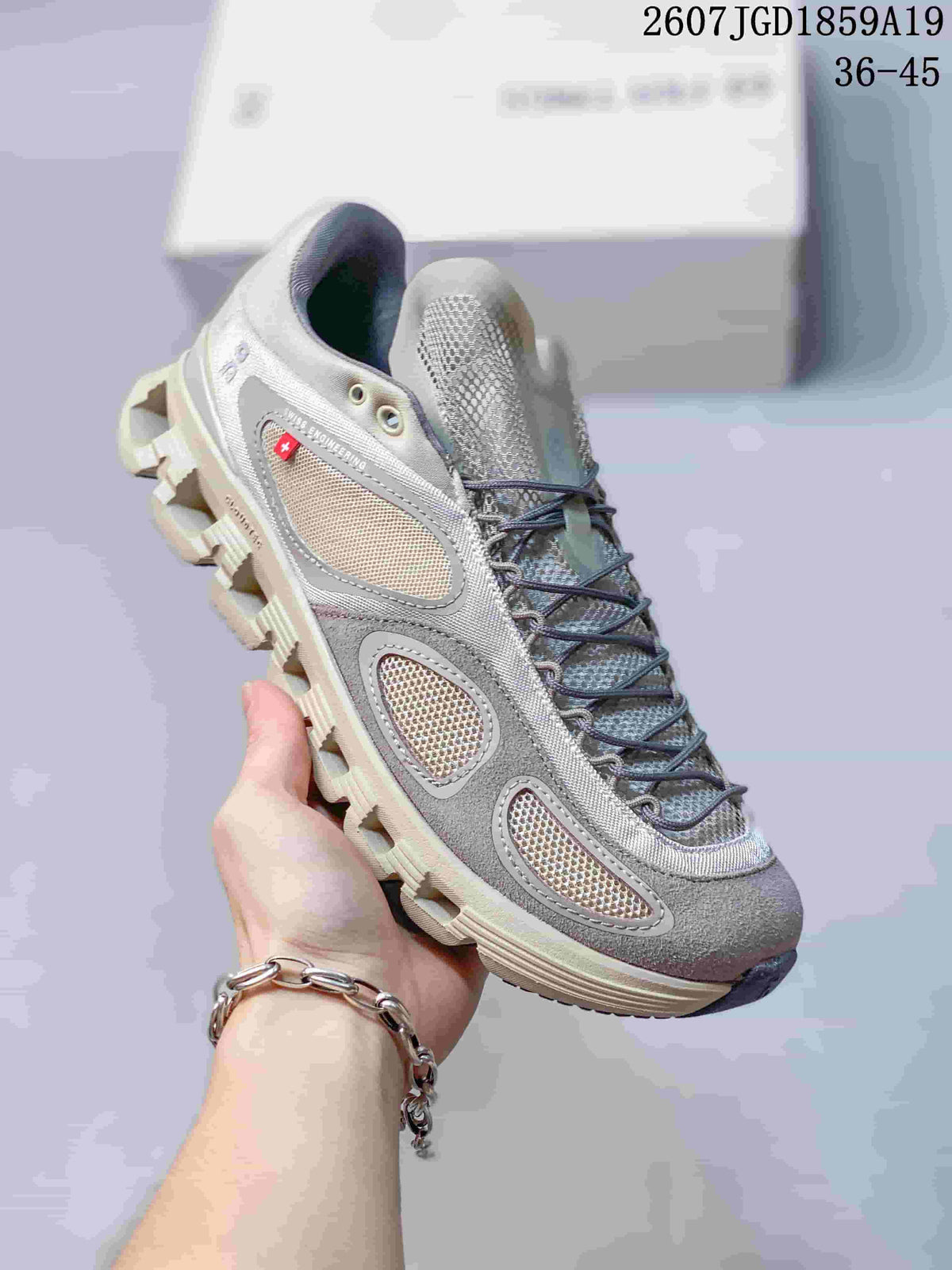 Light gray and beige On sneaker with mesh panels, dark laces, and a pale segmented outsole.