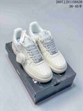 Pair of white Nike Air Force 1 low-top sneakers with grey patterned laces and branded detailing, displayed on a shoebox.