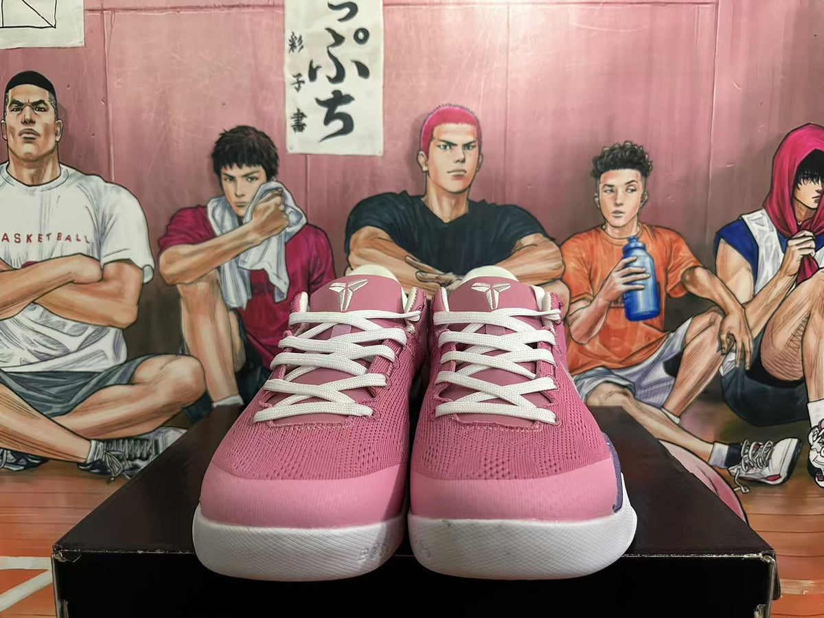 Front view of pink basketball shoes with white laces and Kobe-style tongue logos.