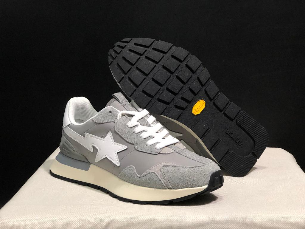 Angled view of one grey sneaker beside its raised outsole, showing the white star emblem and black lugged tread.
