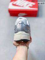 Rear view of the silver and white sneaker showing the padded heel area, Nike branding, and textured outsole edge.
