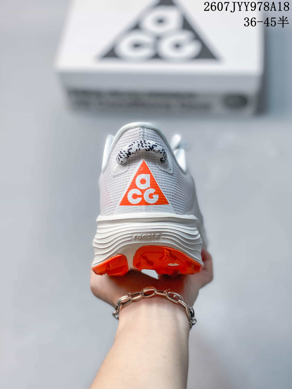 Rear view of a Nike ACG Pegasus Trail shoe showing the orange ACG heel logo and textured white midsole.