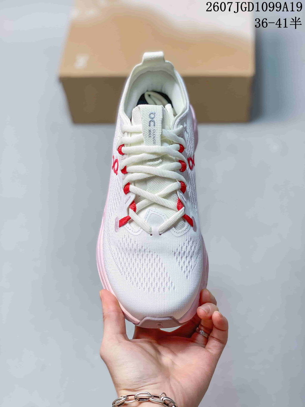 Top view of the white lace-up sneaker showing the tongue, red lace loops and textured toe area.
