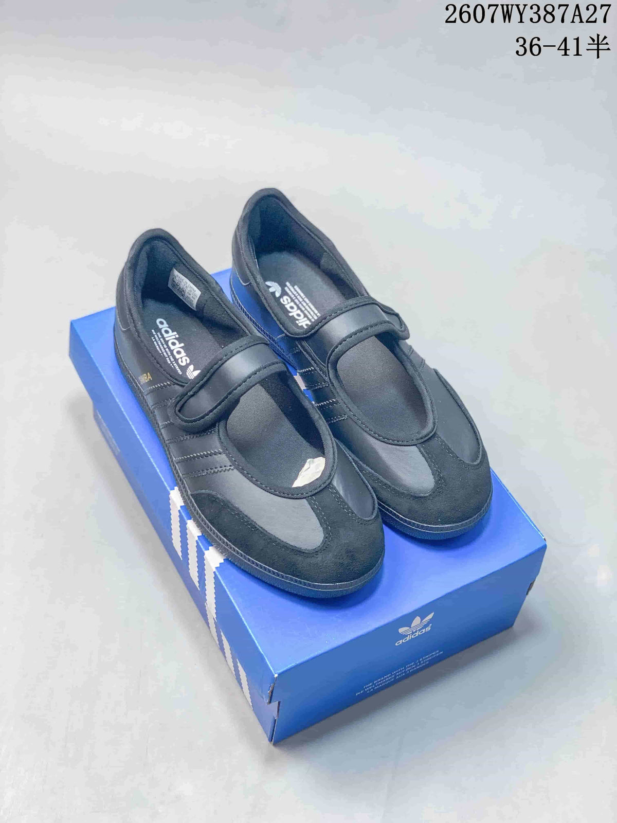 Pair of black adidas Samba Jane sneakers displayed on a blue adidas shoebox, with the hook-and-loop straps visible.