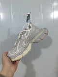 Hand-held side view of eggshell and silver mesh sneakers with gray overlays and cream sole accents.
