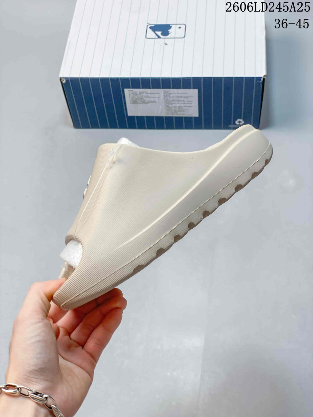Side profile of a beige open-toe slide sandal showing the raised sole and textured upper.