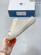 Side profile of a beige open-toe slide sandal showing the raised sole and textured upper.