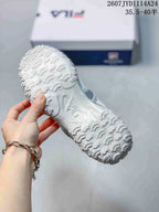 Bottom view showing the sneakers’ textured white outsole and repeating curved tread pattern.