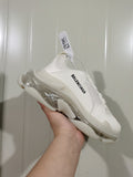 Side view of a white Balenciaga sneaker with black side branding and a clear-look layered sole.