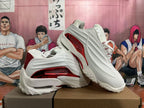 White sneakers with red side accents displayed in an angled view